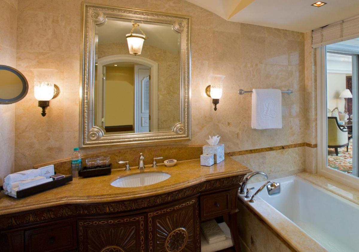 a bathroom with a sink and a tub and a mirror at The Leela Palace Bengaluru in Bengaluru a bathroom with a sink and a tub and a mirror at The Leela Palace Bengaluru in Bengaluru