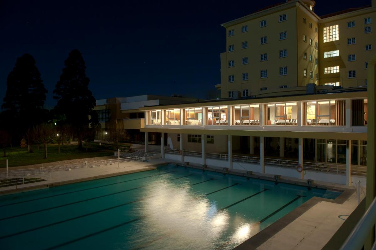 uma piscina em frente a um prédio à noite em Grande Hotel De Luso no Luso