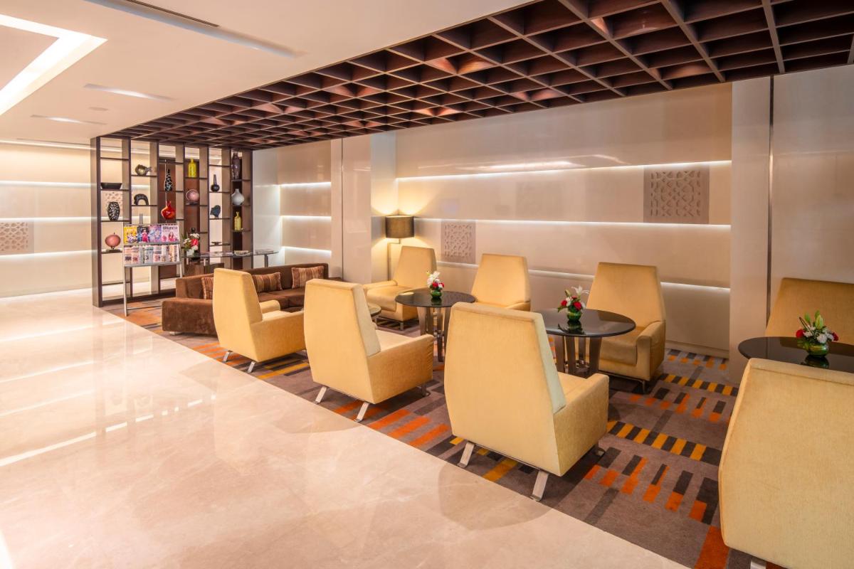 a lobby with chairs and tables in a hotel at Holiday Inn Mumbai International Airport by IHG in Mumbai