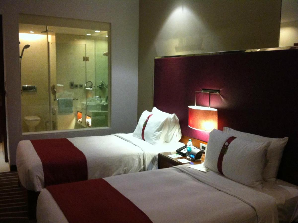 a hotel room with two beds and a shower at Holiday Inn Mumbai International Airport by IHG in Mumbai