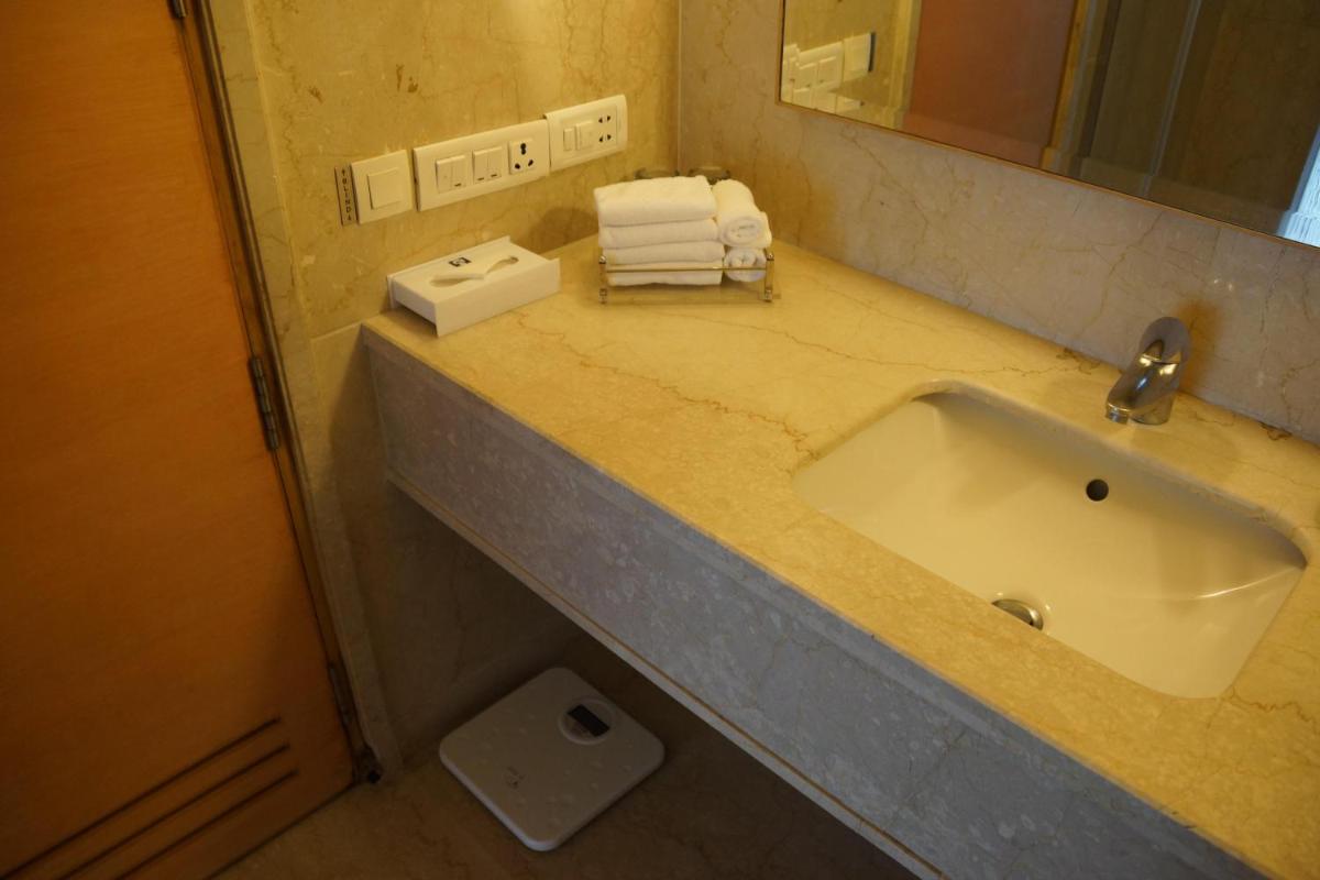 a bathroom counter with a sink and a mirror at Jaypee Vasant Continental in New Delhi