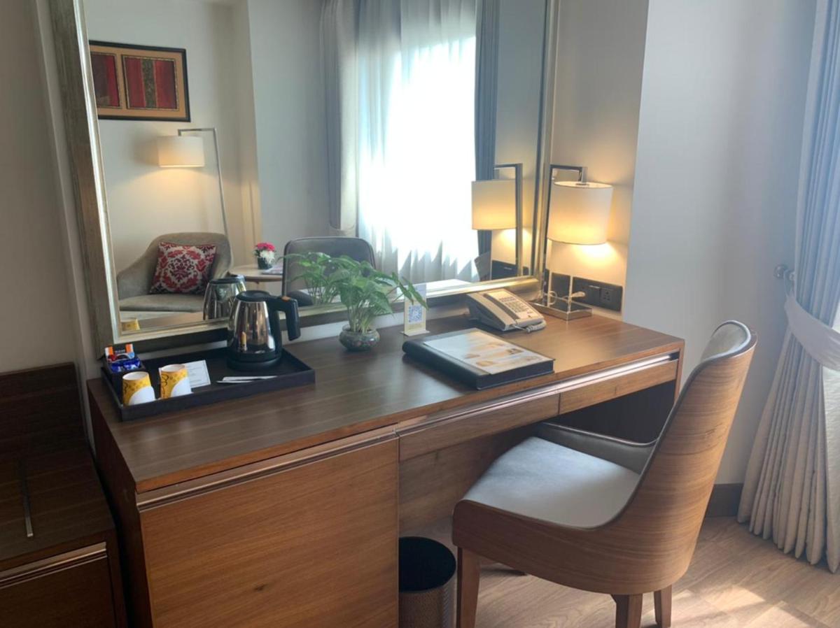 a desk with a mirror and a chair in a room at Jaypee Vasant Continental in New Delhi