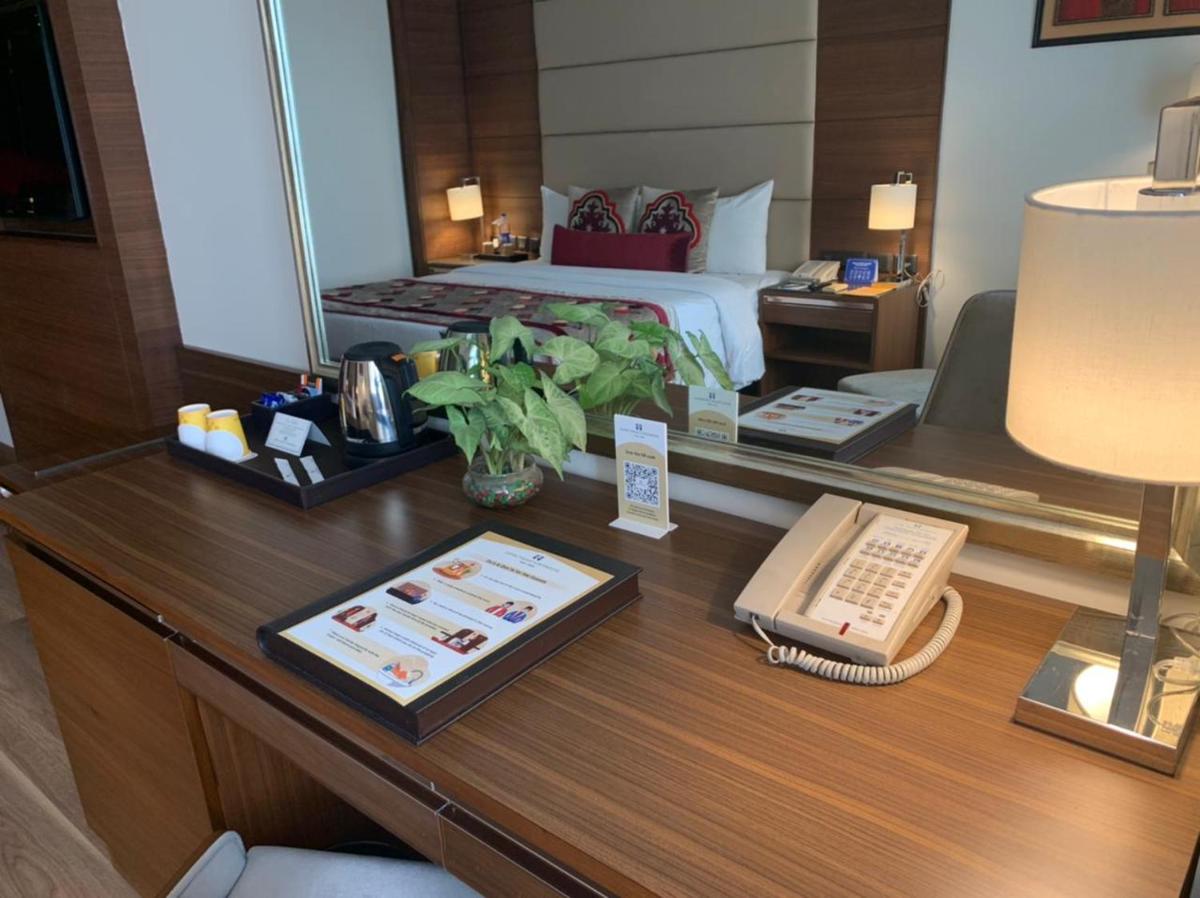 a hotel room with a bed and a desk with a phone at Jaypee Vasant Continental in New Delhi