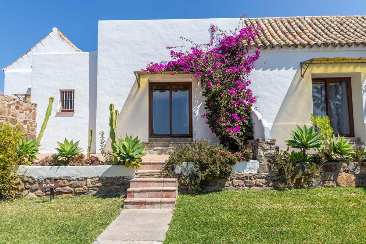 Una casa blanca con flores a un lado. en El Cortijo de Zahara by QHotels, en Zahara de los Atunes