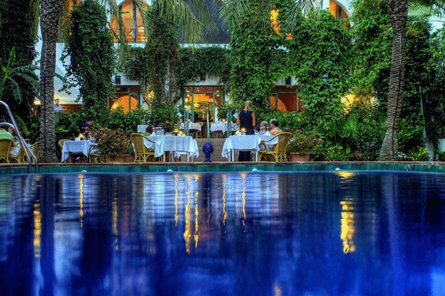 un grupo de personas sentadas en mesas cerca de una piscina en Hurricane Beach Hotel, en Tarifa