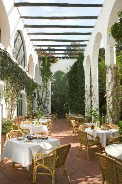 un patio al aire libre con mesas, sillas y techo en Hurricane Beach Hotel, en Tarifa 22 fotos más