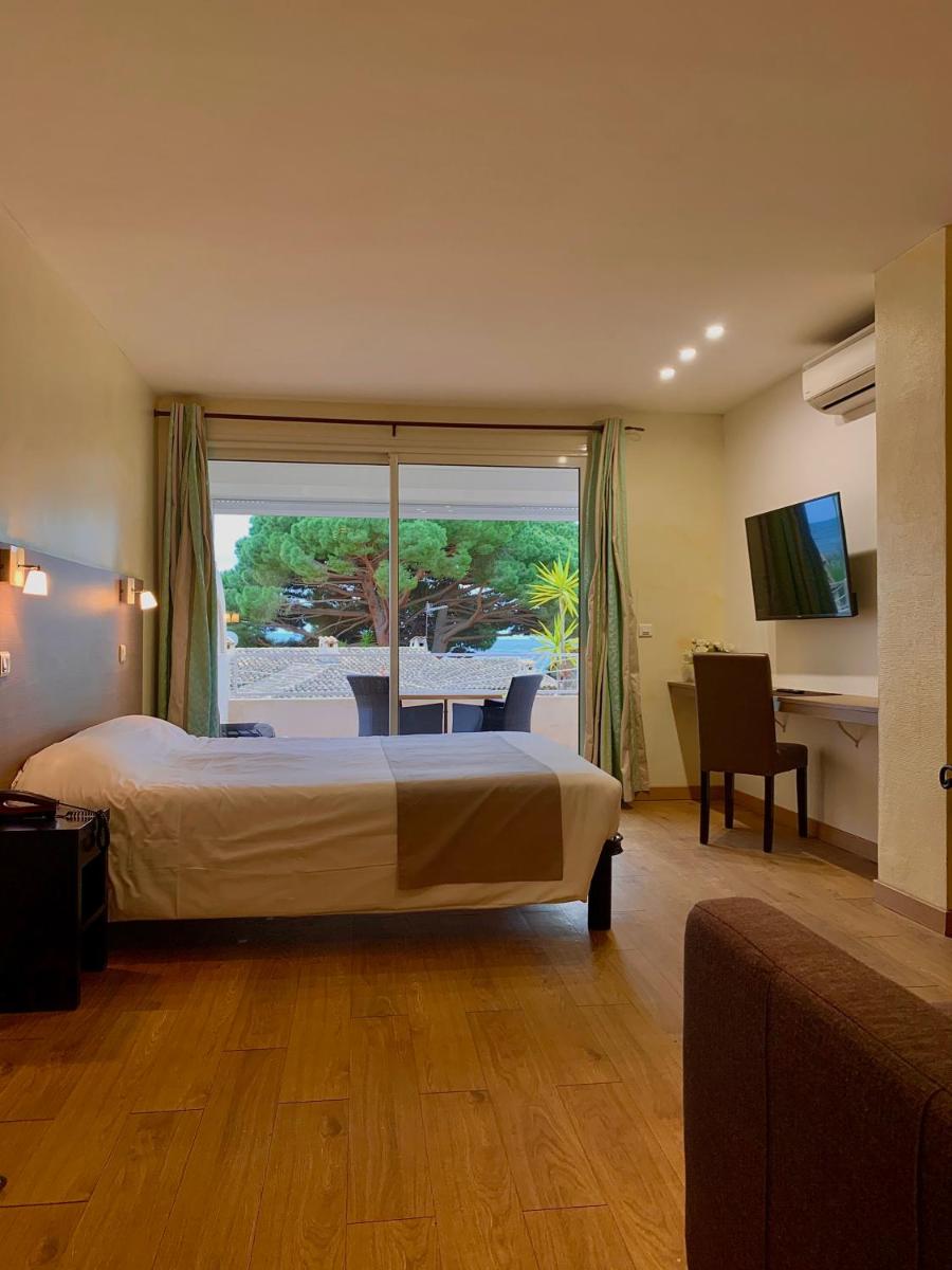 une chambre d'hôtel avec un lit et une grande fenêtre dans l'établissement Hôtel Beau Soleil, au Lavandou