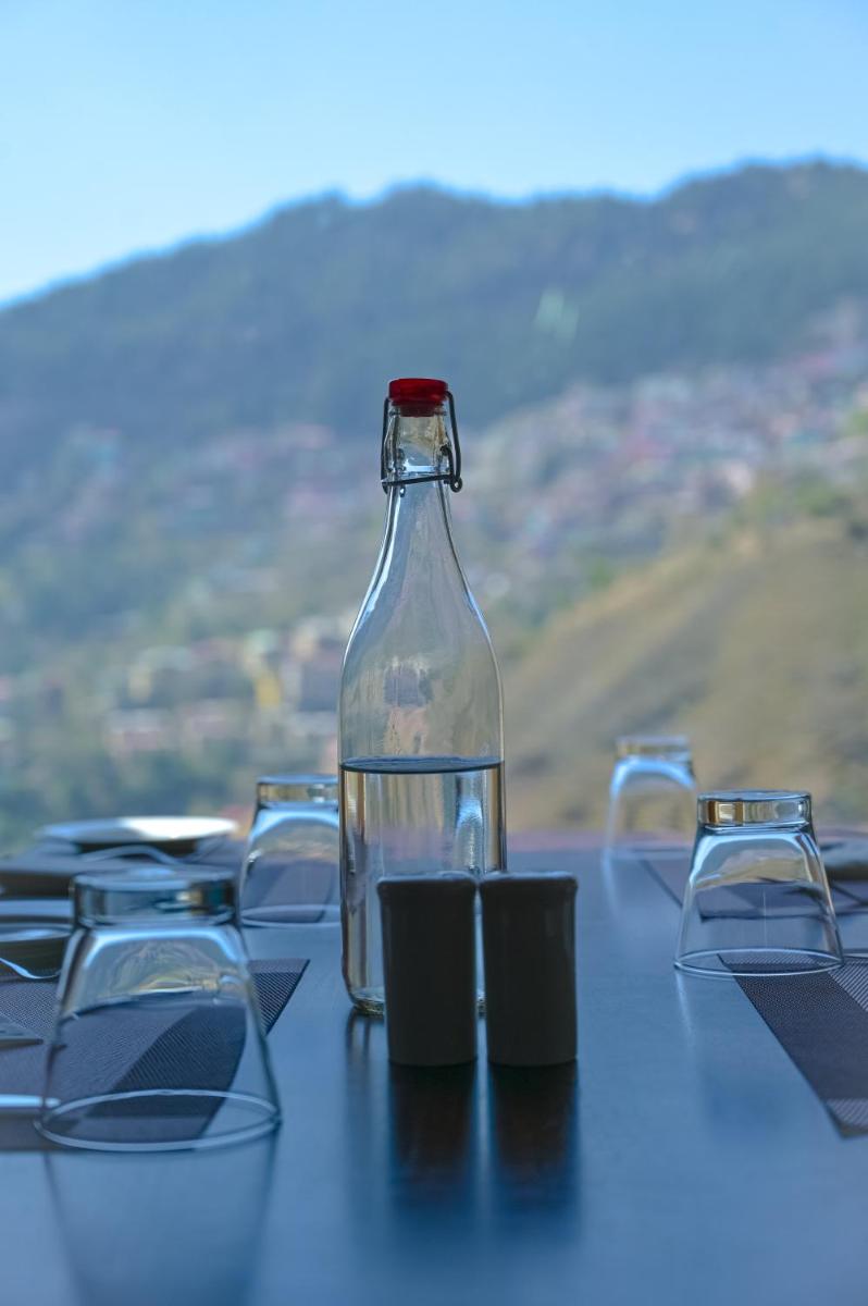 a glass bottle sitting on top of a table with glasses at The Orchid Shimla in Shimla