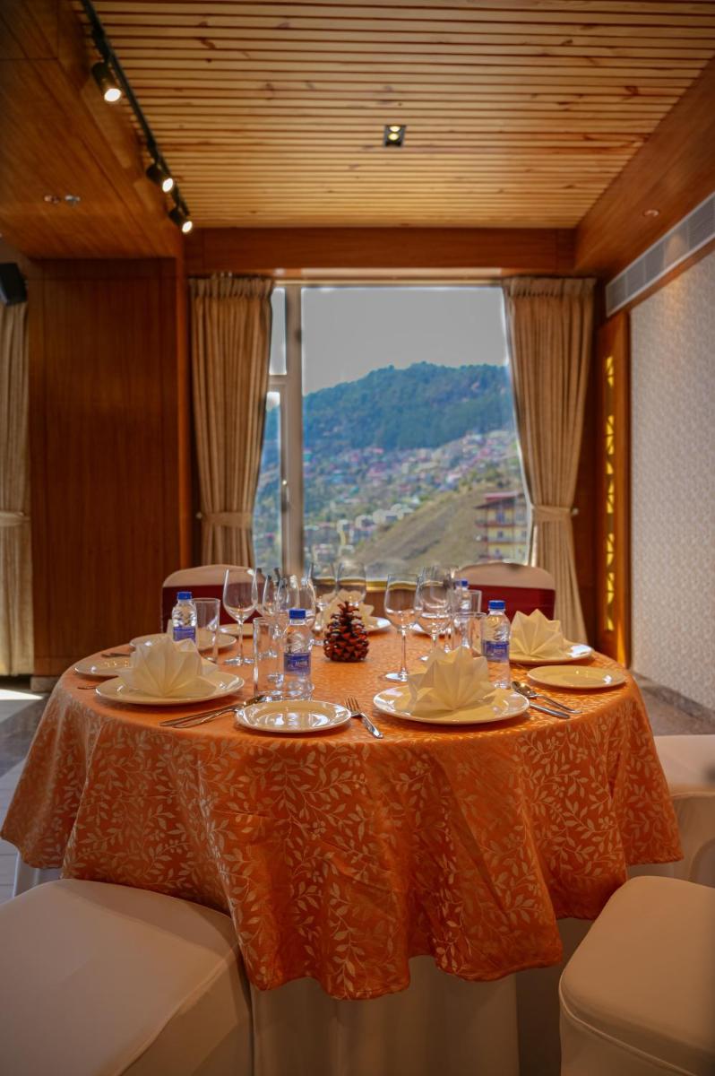 a table with wine glasses on it with a view at The Orchid Shimla in Shimla