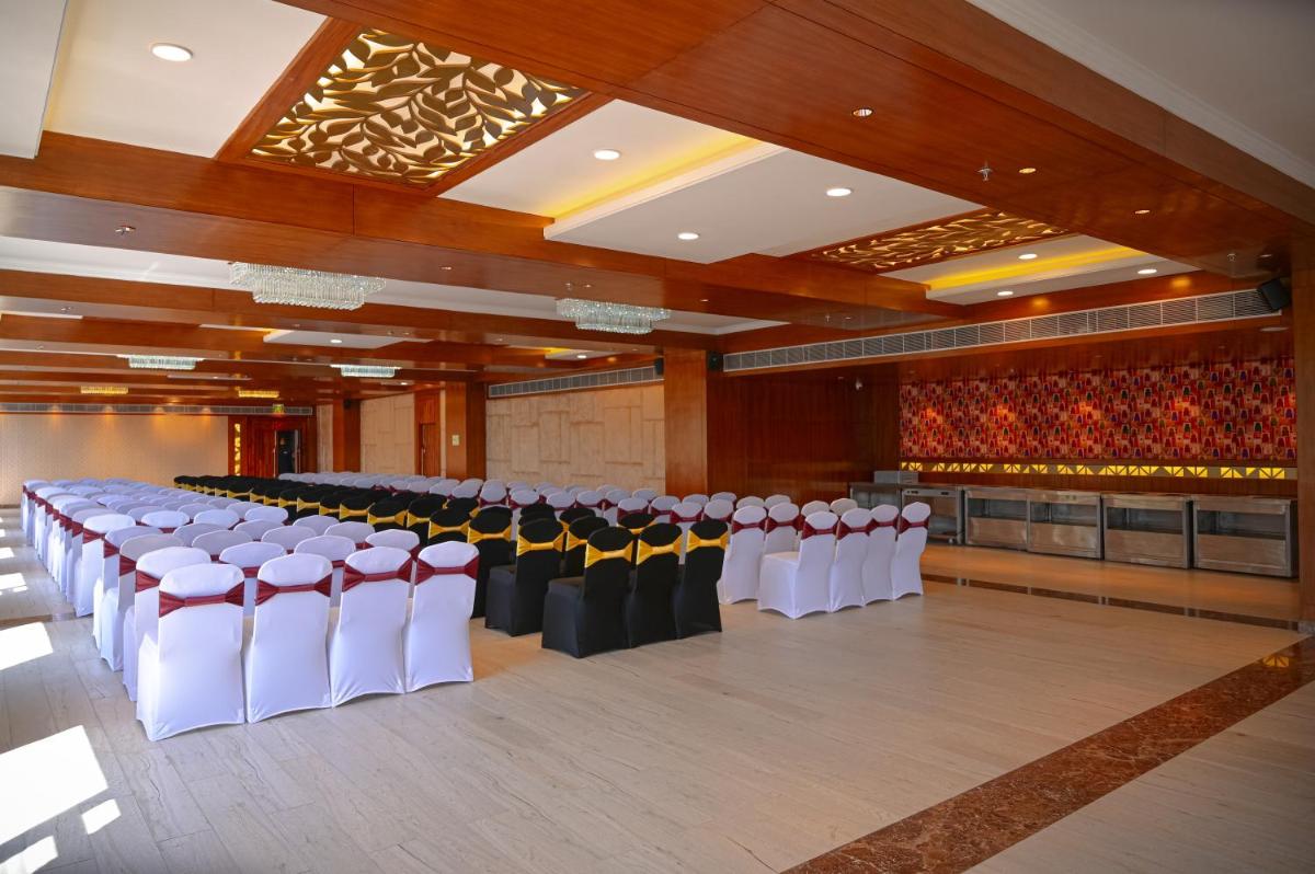 a banquet hall with white and black chairs and tables at The Orchid Shimla in Shimla