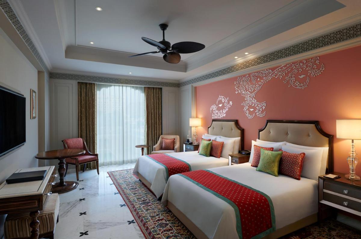 a hotel room with two beds and a television at The Leela Palace Jaipur in Jaipur