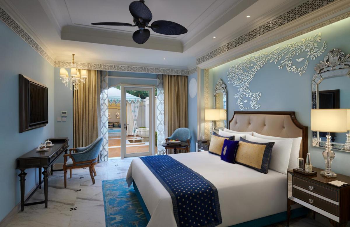 a bedroom with a bed and a desk and a room at The Leela Palace Jaipur in Jaipur