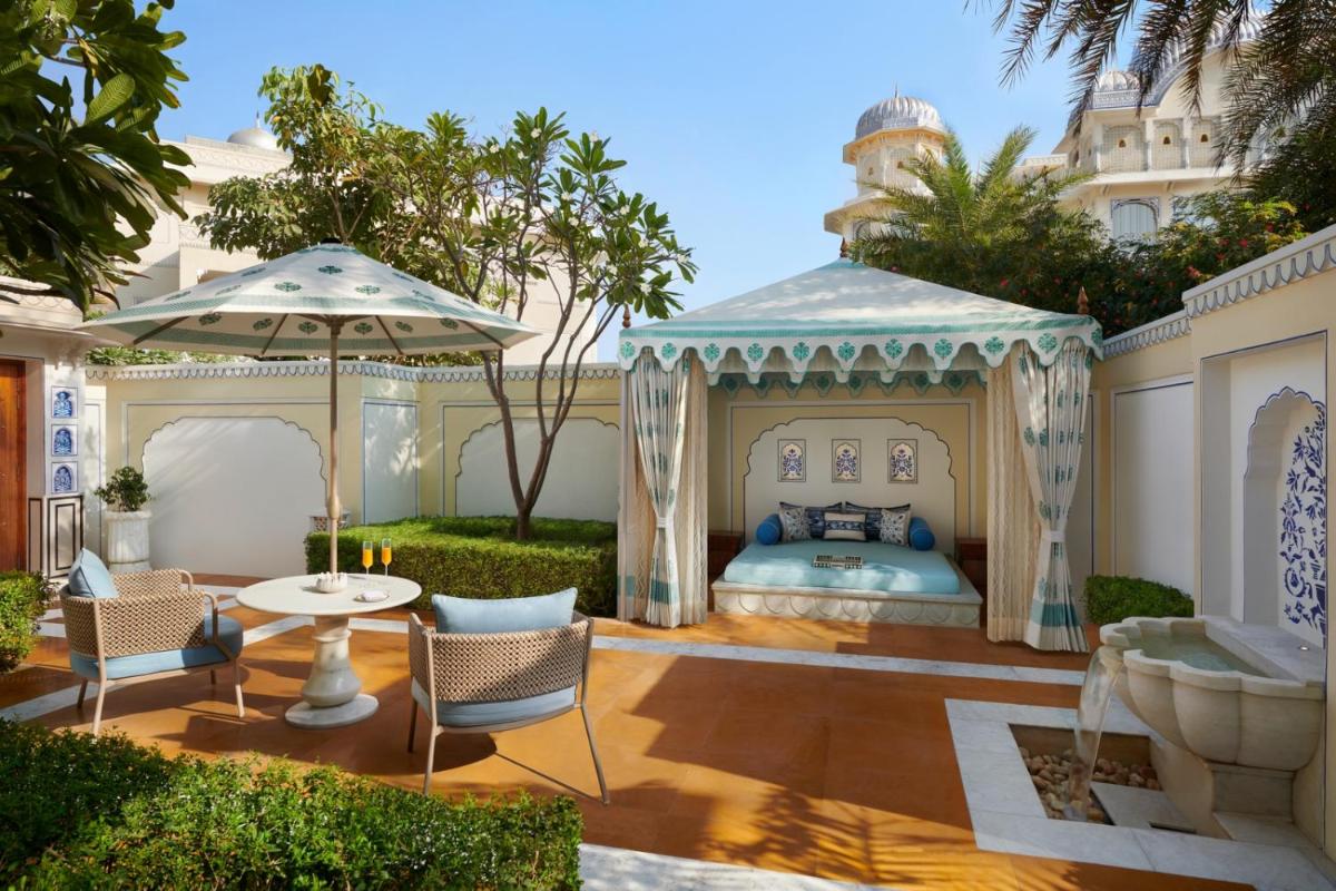 a bedroom in a villa with a bed and a table at The Leela Palace Jaipur in Jaipur