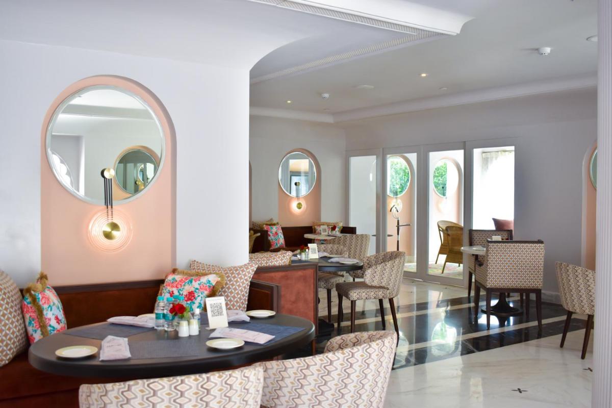 a dining room with tables and chairs and mirrors at The Leela Palace Jaipur in Jaipur