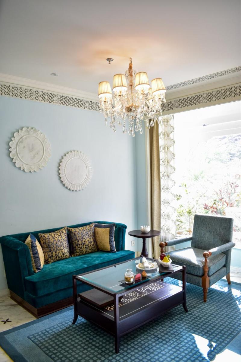 a living room with a green couch and a chandelier at The Leela Palace Jaipur in Jaipur