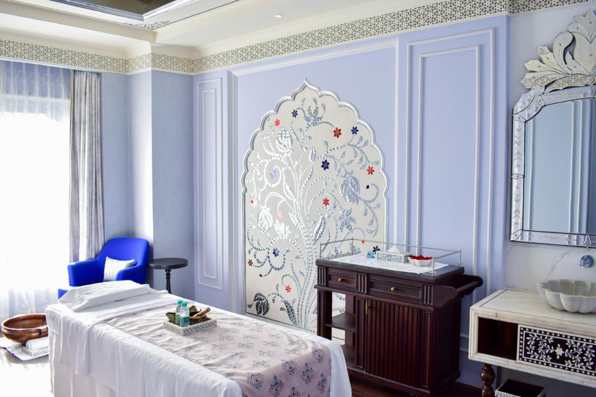 a room with a bed and a table and a mirror at The Leela Palace Jaipur in Jaipur