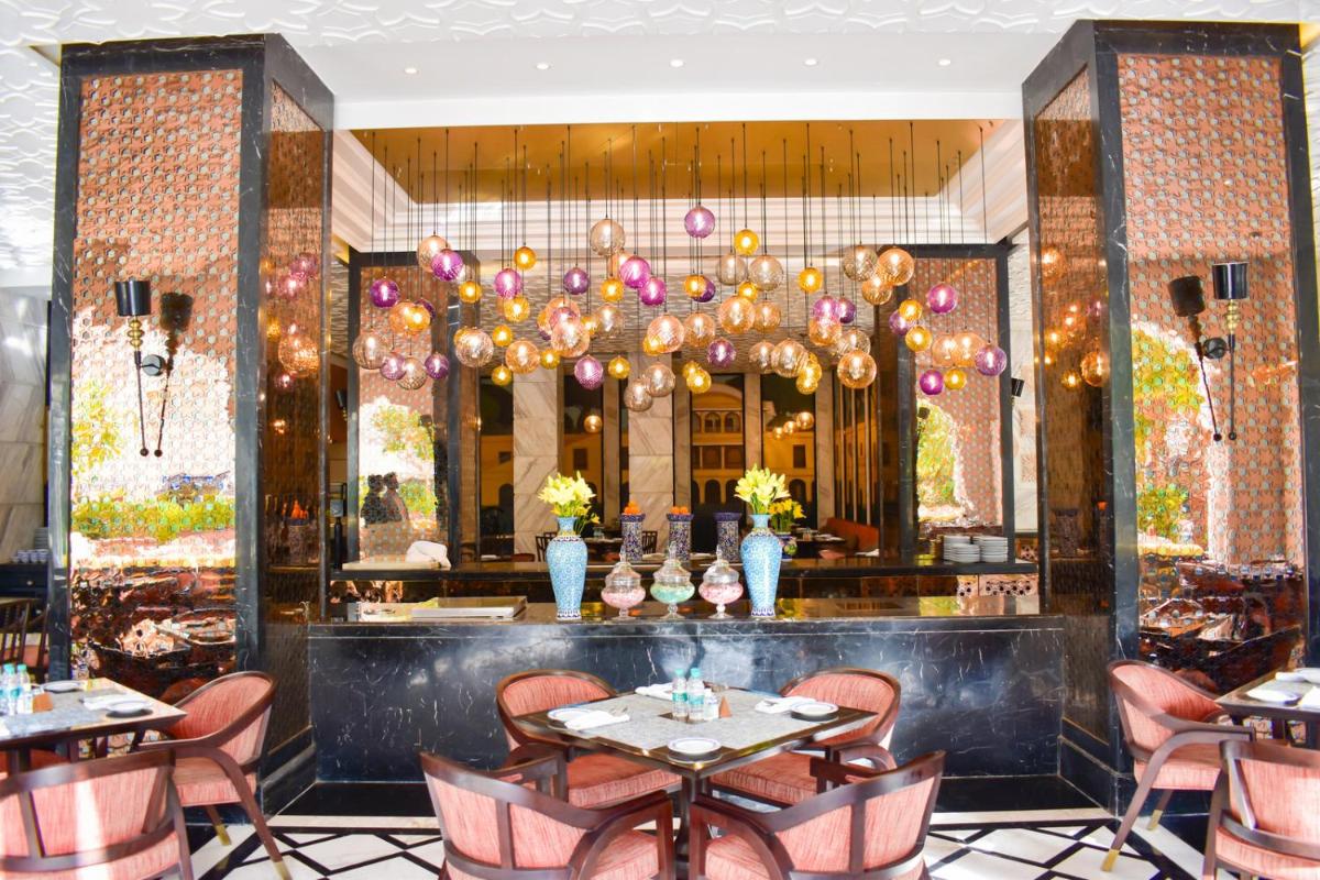 a restaurant with tables and chairs and a chandelier at The Leela Palace Jaipur in Jaipur