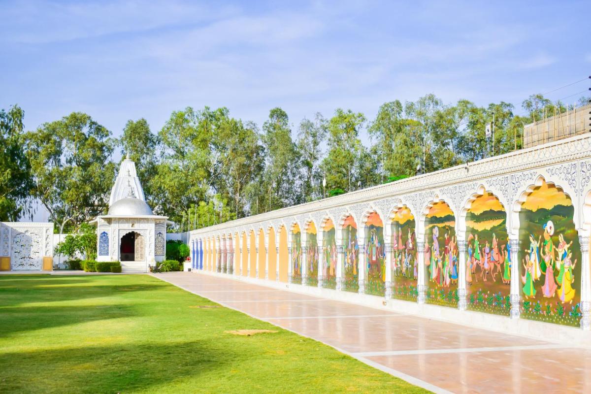 a wall with paintings on it in a park at The Leela Palace Jaipur in Jaipur