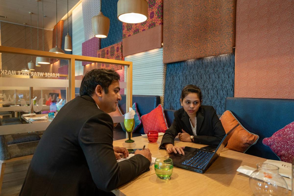 a man and woman sitting at a table with a laptop at Welcomhotel by ITC Hotels, RaceCourse, Coimbatore in Coimbatore