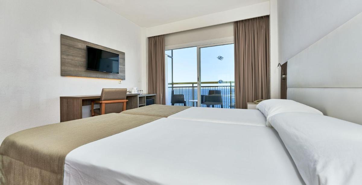 Una habitación de hotel con una cama grande y un televisor. en Globales Cala Viñas Adults Only 16+, en Cala Vinyes