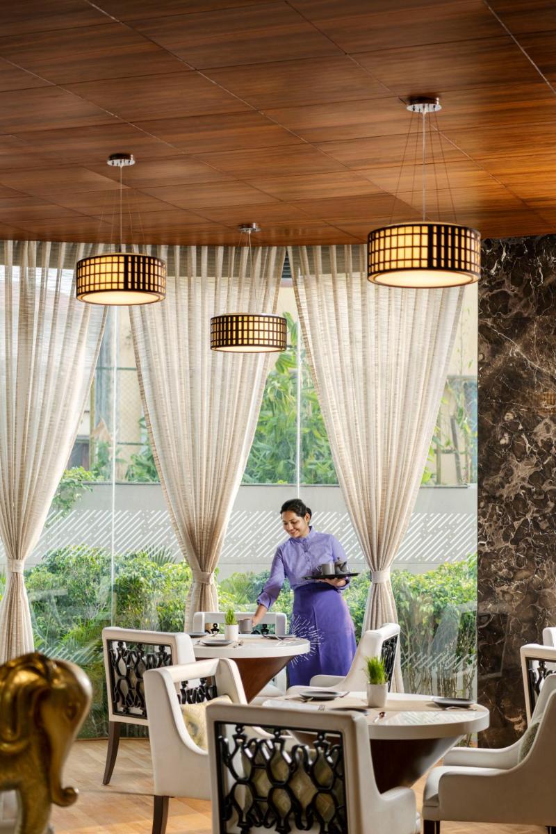 a woman standing at a table in a restaurant at Vivanta Thiruvananthapuram in Trivandrum