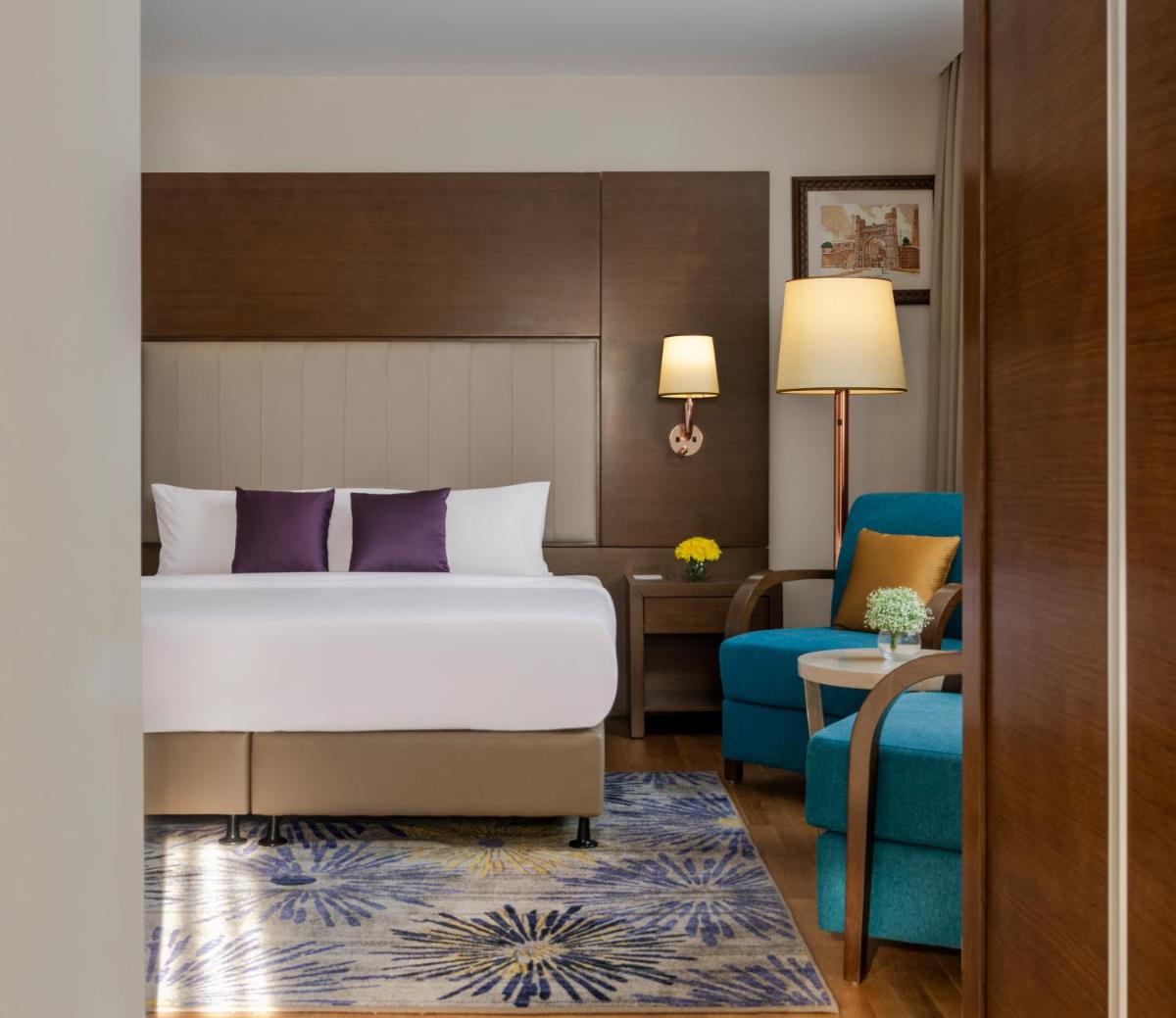 a hotel room with a bed and a blue couch at Vivanta Thiruvananthapuram in Trivandrum