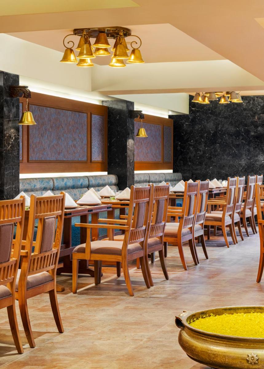 a dining room with wooden tables and chairs at Vivanta Thiruvananthapuram in Trivandrum