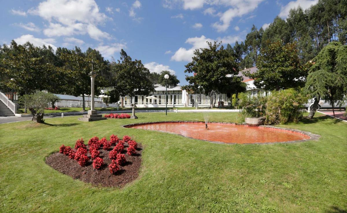 Un parque con un ramo de flores rojas en el césped. en Hotel Spa Congreso, en Teo