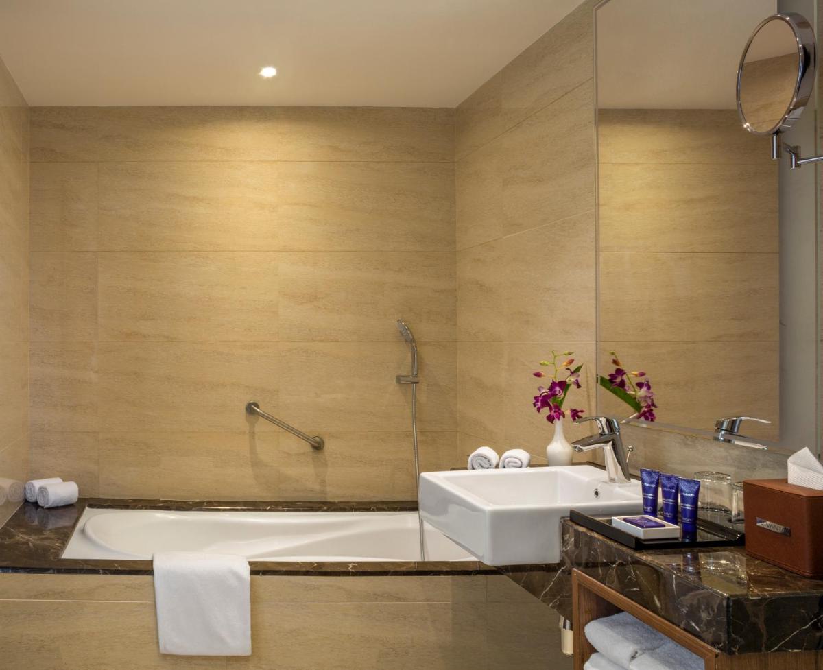 a bathroom with a bath tub and a sink at Vivanta Thiruvananthapuram in Trivandrum a bathroom with a bath tub and a sink at Vivanta Thiruvananthapuram in Trivandrum