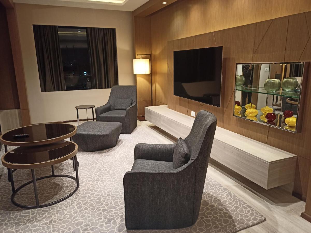 a living room with a tv and chairs and a table at Welcomhotel by ITC Hotels, Richmond Road, Bengaluru in Bengaluru