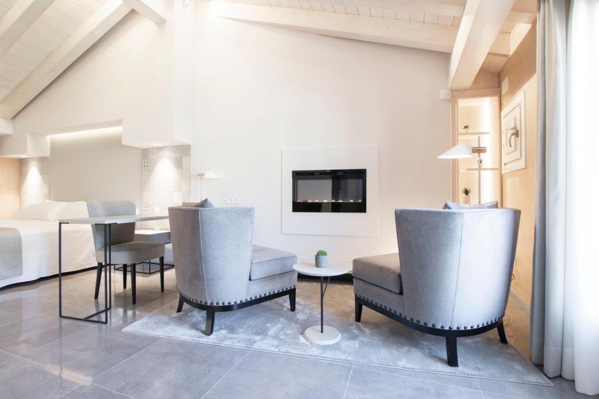 Una sala de estar con una mesa y sillas y una cama. en Hotel 1877 Sensaciones & SPA ADULTS ONLY, en Albarracín