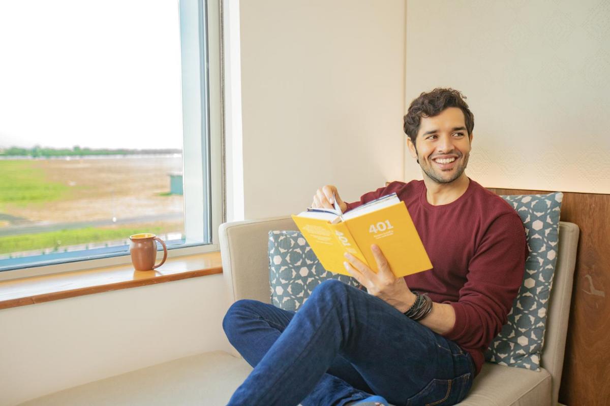 a man sitting on a couch reading a book at Andaz Delhi, by Hyatt in New Delhi a man sitting on a couch reading a book at Andaz Delhi, by Hyatt in New Delhi