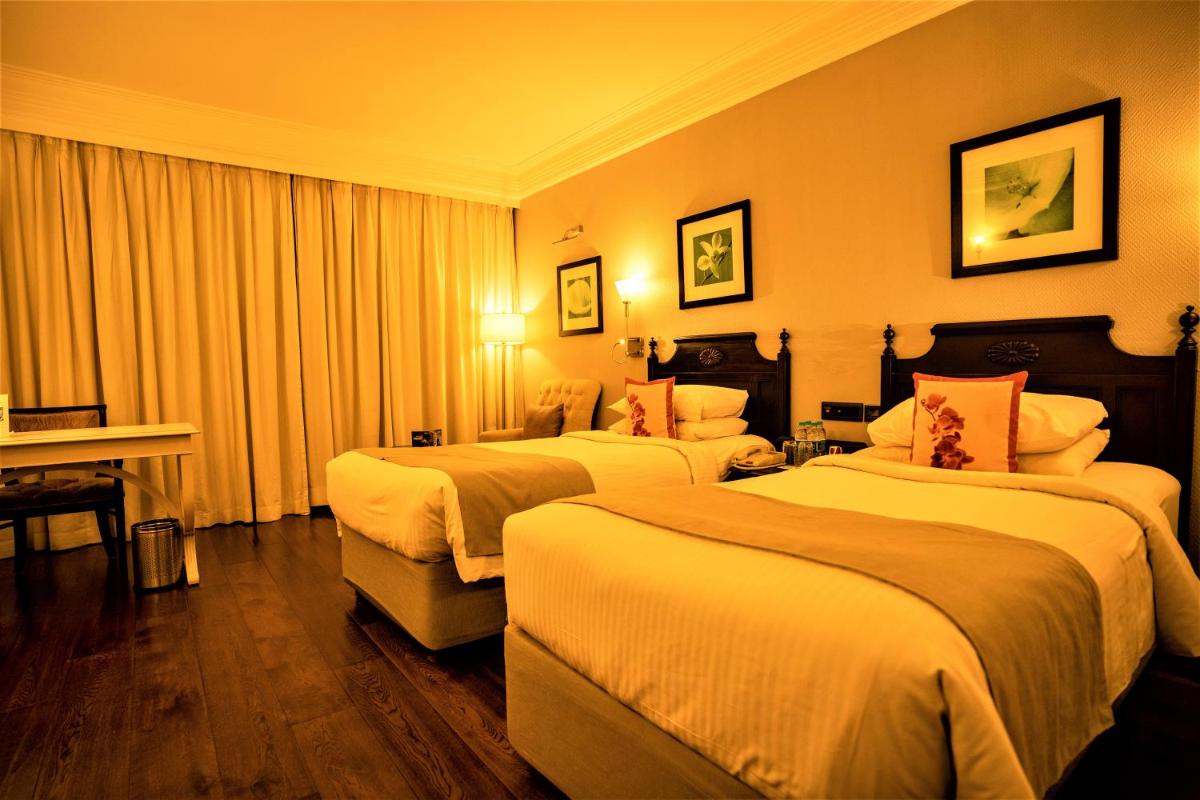 a hotel room with two beds and a piano at Hotel Royal Orchid Bangalore in Bengaluru