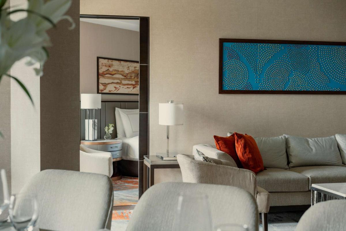 a living room with a couch and chairs and a mirror at Shangri-La Eros New Delhi in New Delhi a living room with a couch and chairs and a mirror at Shangri-La Eros New Delhi in New Delhi