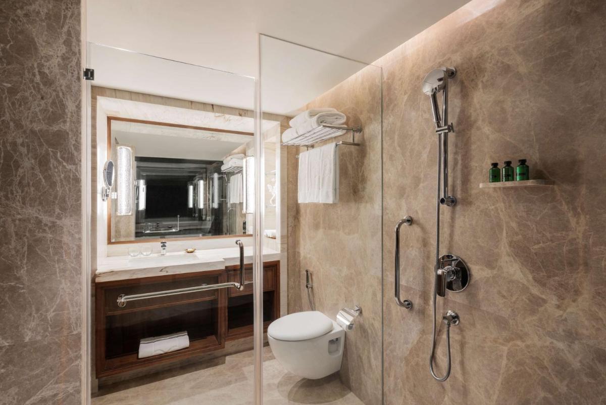 a bathroom with a shower and a toilet and a sink at Shangri-La Eros New Delhi in New Delhi a bathroom with a shower and a toilet and a sink at Shangri-La Eros New Delhi in New Delhi