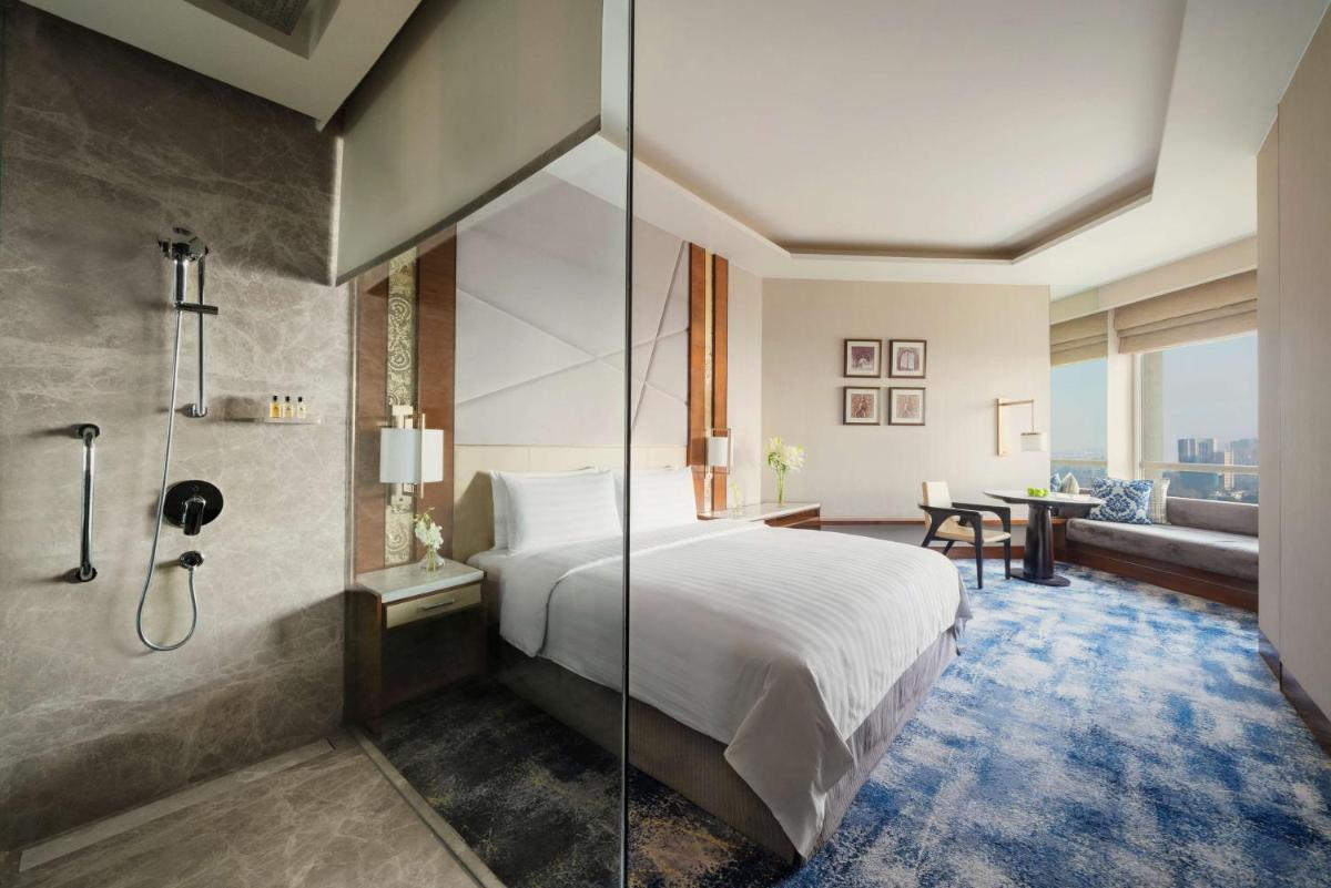 a hotel room with a bed and a shower at Shangri-La Eros New Delhi in New Delhi a hotel room with a bed and a shower at Shangri-La Eros New Delhi in New Delhi