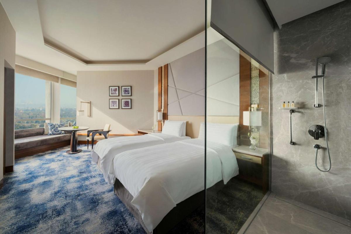 a hotel room with a large bed and a shower at Shangri-La Eros New Delhi in New Delhi a hotel room with a large bed and a shower at Shangri-La Eros New Delhi in New Delhi