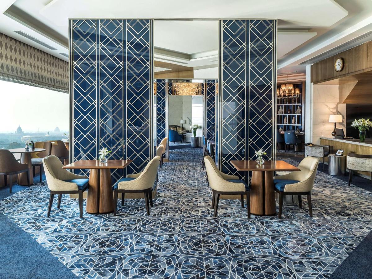 a lobby of a hotel with tables and chairs at Shangri-La Eros New Delhi in New Delhi a lobby of a hotel with tables and chairs at Shangri-La Eros New Delhi in New Delhi