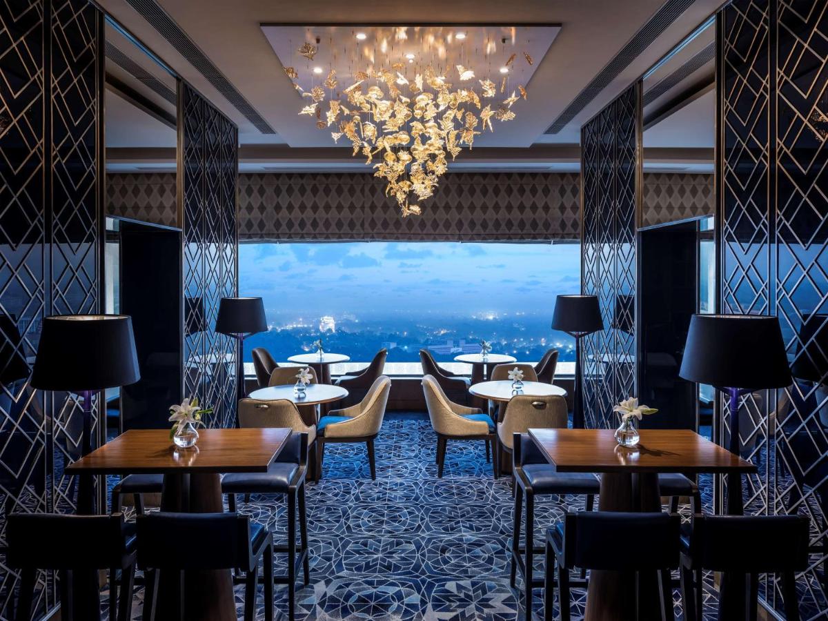 a restaurant with tables and chairs and a chandelier at Shangri-La Eros New Delhi in New Delhi a restaurant with tables and chairs and a chandelier at Shangri-La Eros New Delhi in New Delhi