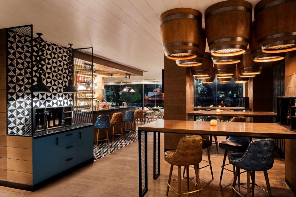 a restaurant with a bar with tables and chairs at Shangri-La Eros New Delhi in New Delhi a restaurant with a bar with tables and chairs at Shangri-La Eros New Delhi in New Delhi