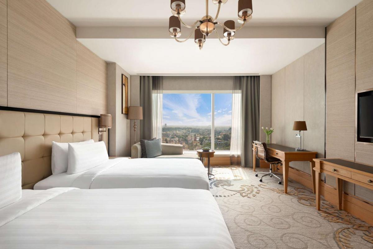 a hotel room with two beds and a television at Shangri-La Bengaluru in Bengaluru a hotel room with two beds and a television at Shangri-La Bengaluru in Bengaluru