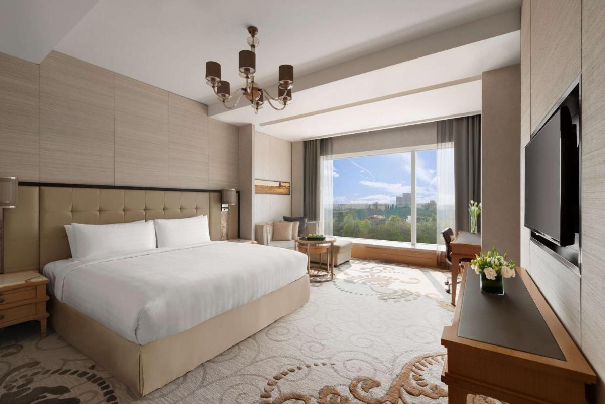 a hotel room with a bed and a large window at Shangri-La Bengaluru in Bengaluru a hotel room with a bed and a large window at Shangri-La Bengaluru in Bengaluru