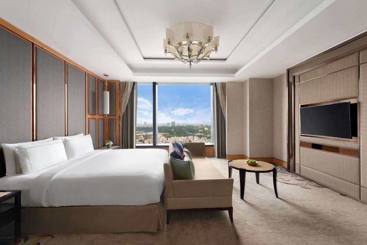 a hotel room with a large bed and a chandelier at Shangri-La Bengaluru in Bengaluru a hotel room with a large bed and a chandelier at Shangri-La Bengaluru in Bengaluru