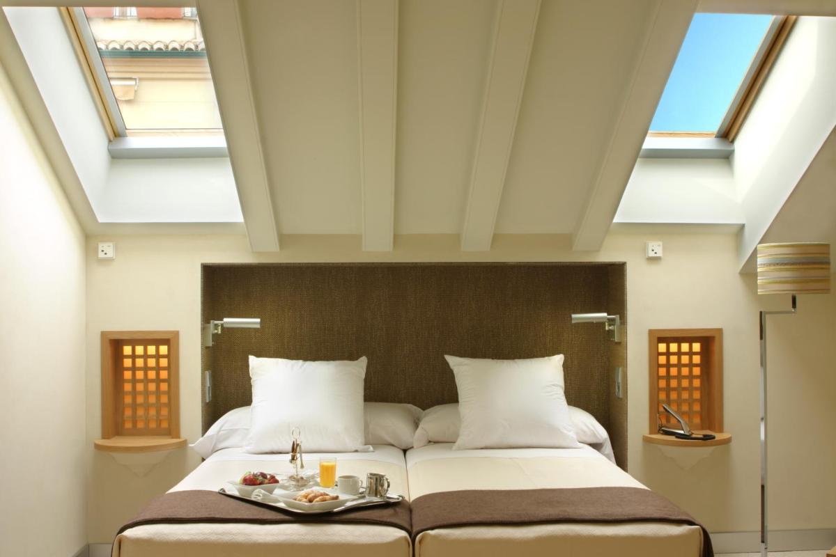 Cama grande en habitación con tragaluces en Villa Oniria, en Granada