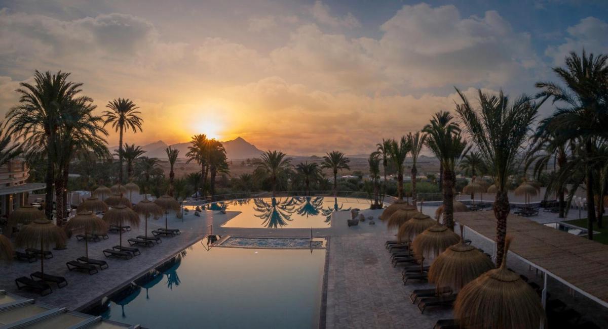 un complejo con piscina, palmeras y puesta de sol en Balneario de Leana, en Fortuna
