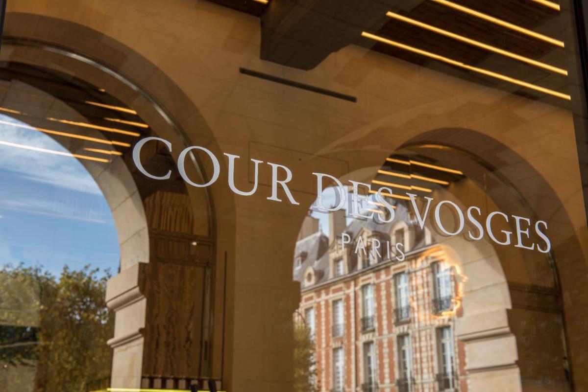 une vitrine avec les mots « nos chiens et leurs fidèles » dans l'établissement Cour des Vosges - Evok Collection, à Paris une vitrine avec les mots « nos chiens et leurs fidèles » dans l'établissement Cour des Vosges - Evok Collection, à Paris