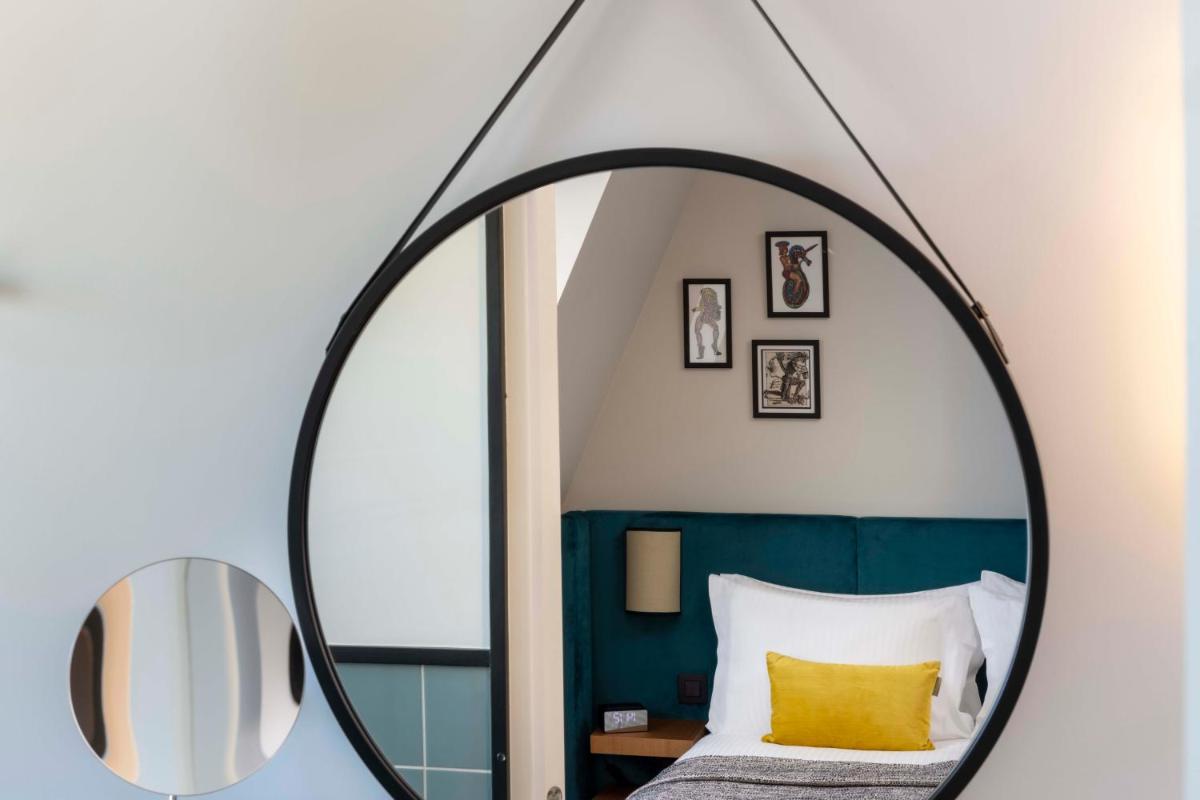 - un miroir rond dans une chambre avec un lit dans l'établissement Hotel Le 37 Bis, à Neuilly-sur-Seine