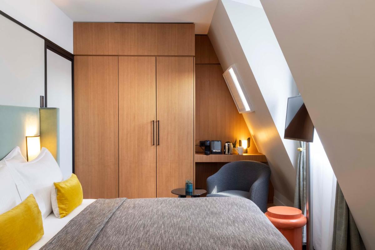 Cette chambre comprend un lit, une chaise et une armoire. dans l'établissement Hotel Le 37 Bis, à Neuilly-sur-Seine 30 autres photos