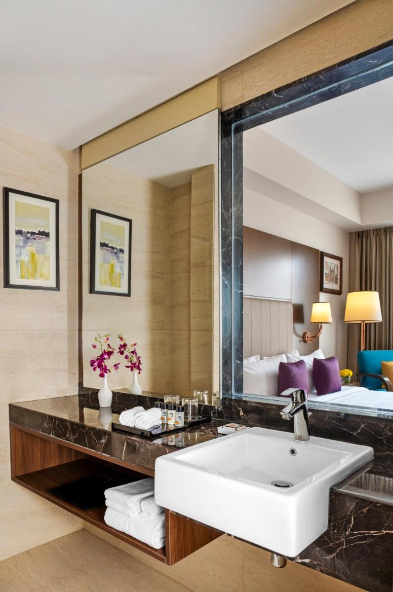 a bathroom with a sink and a large mirror at Vivanta Thiruvananthapuram in Trivandrum