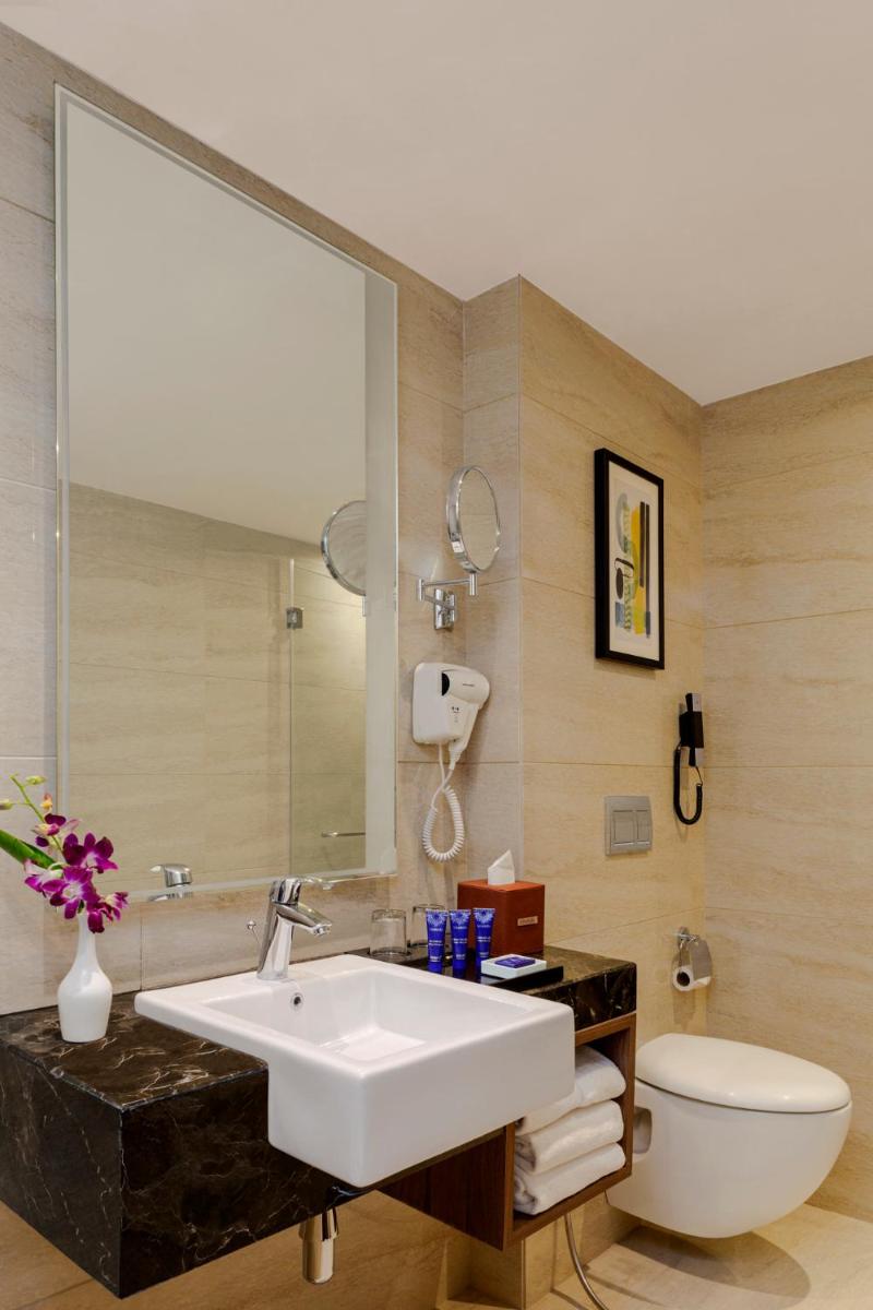 a bathroom with a sink and a toilet and a mirror at Vivanta Thiruvananthapuram in Trivandrum